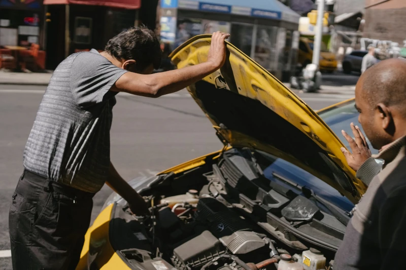 Dois homens olhando para o motor de um carro amarelo